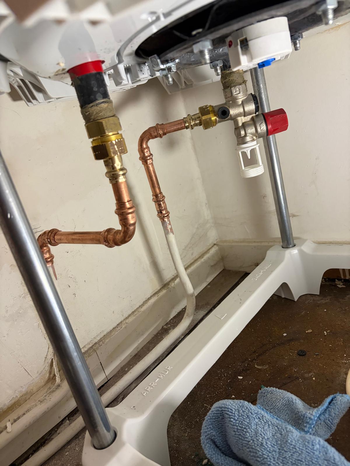 Raccordements cuivre et groupe de sécurité sous un chauffe-eau